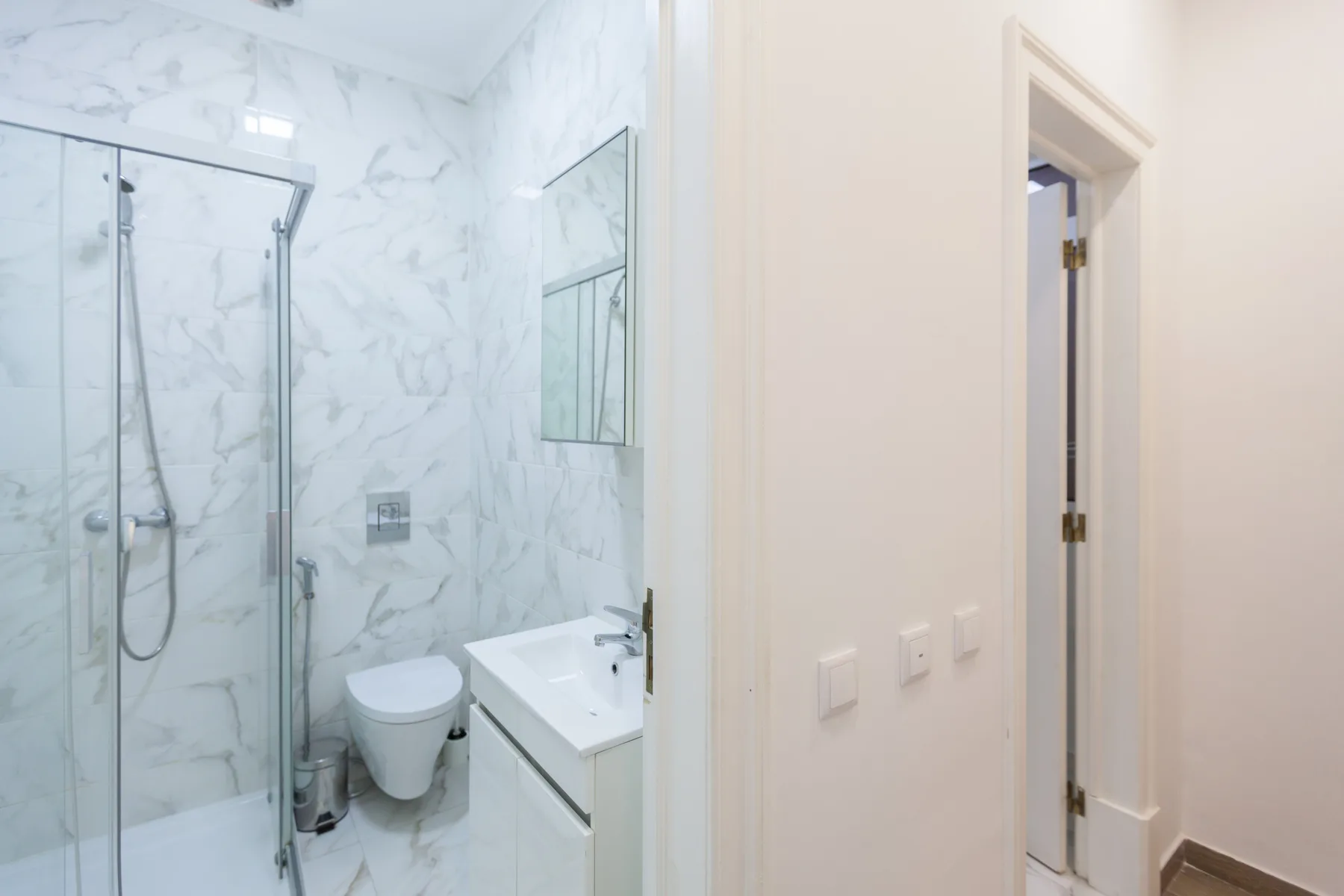 Un baño luminoso con ducha de vidrio y lavabo.