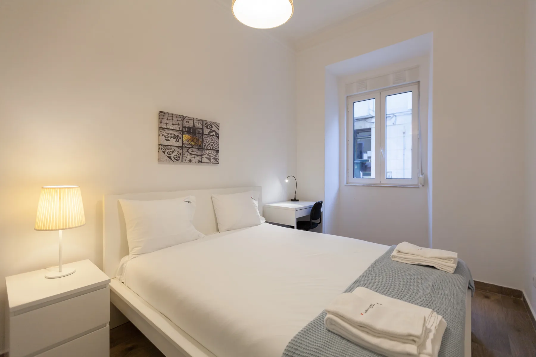 Un dormitorio con una cama doble, mesillas de noche y una ventana.