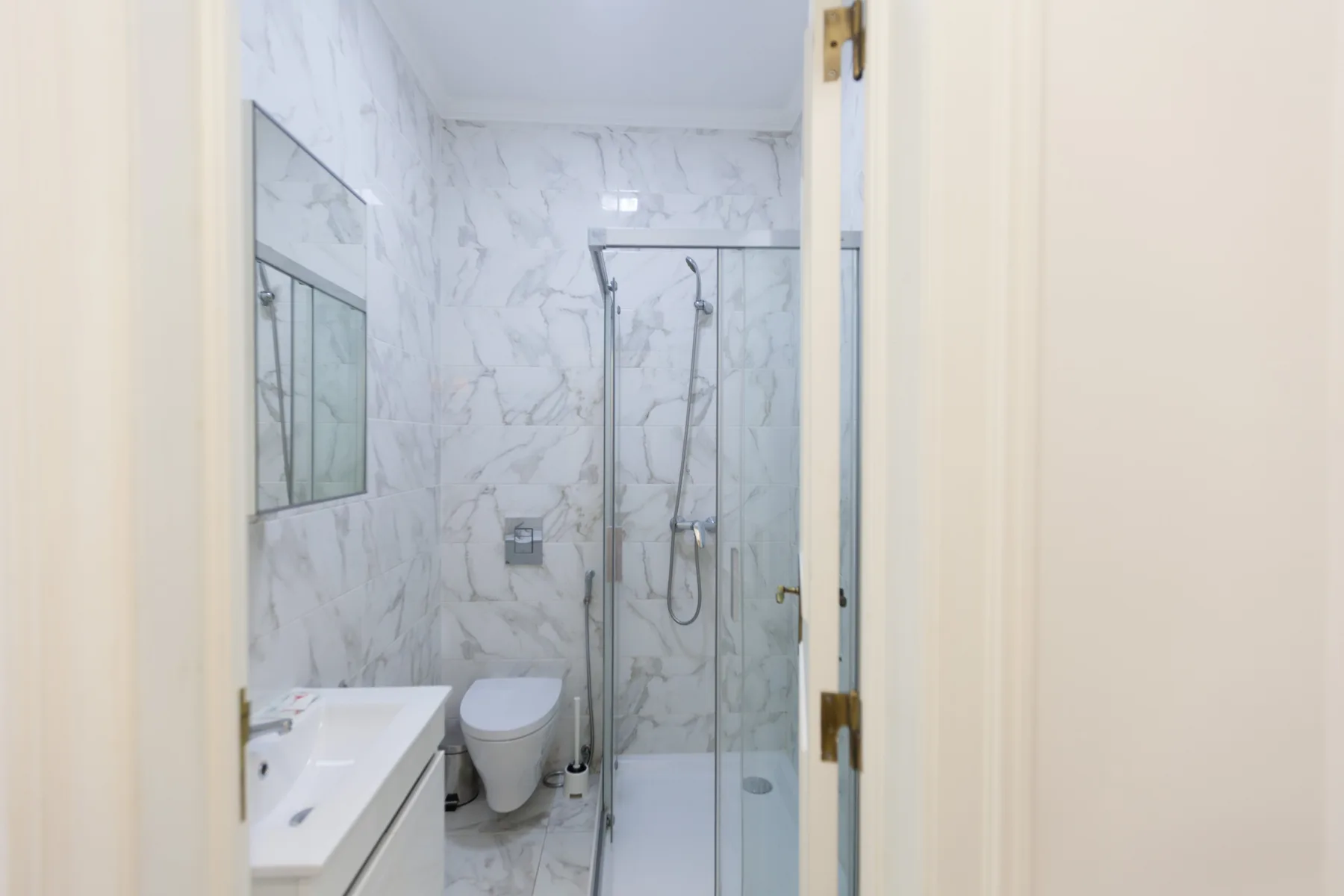Un baño luminoso con lavabo, inodoro y ducha de cristal.