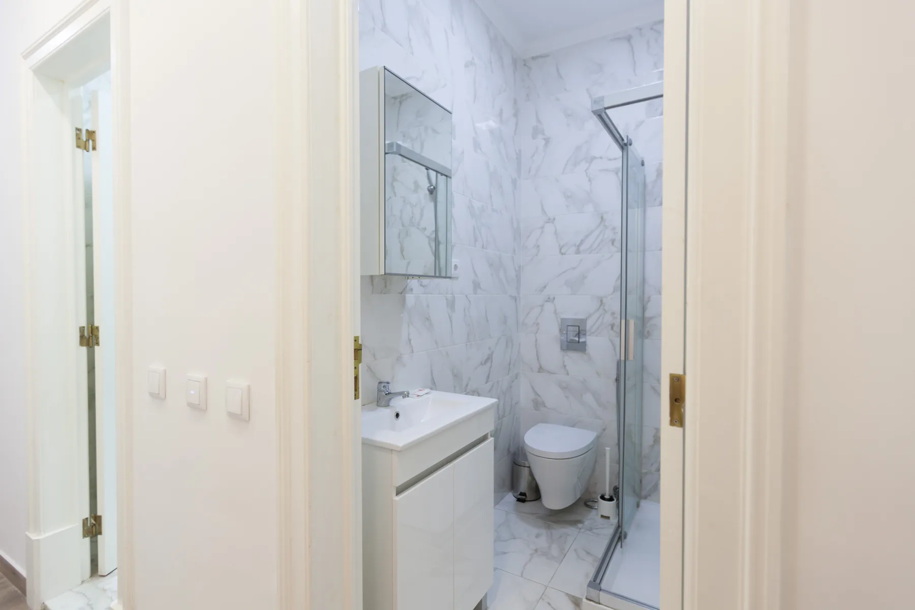 A bright bathroom with a vanity, toilet, and glass shower.