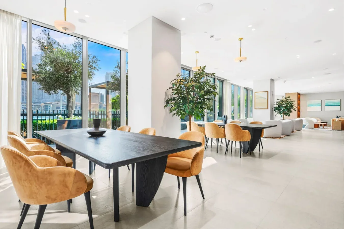 Una luminosa zona de comedor y descanso con una mesa larga junto a grandes ventanales.