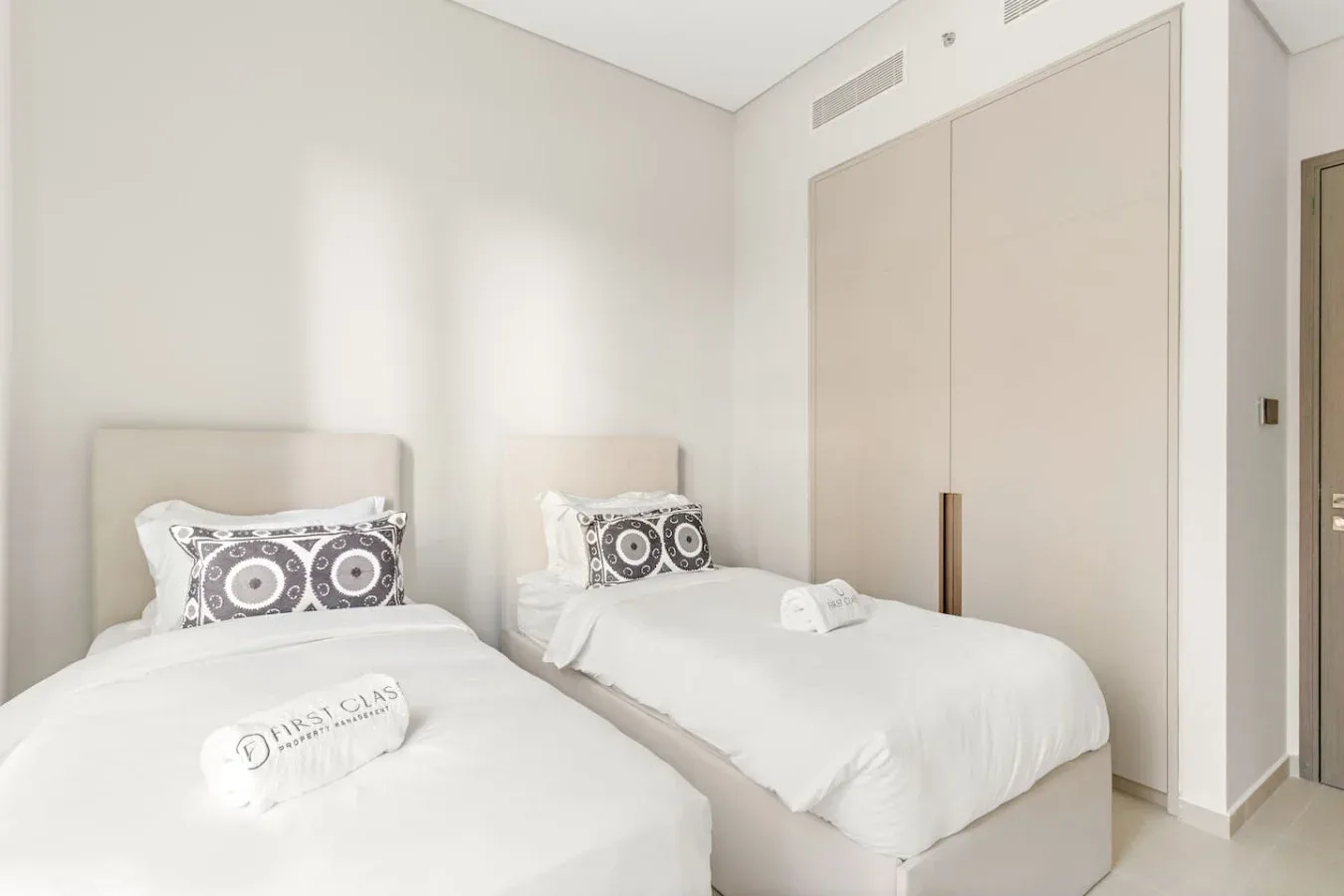 Un dormitorio luminoso con dos camas vestidas con ropa de cama blanca.
