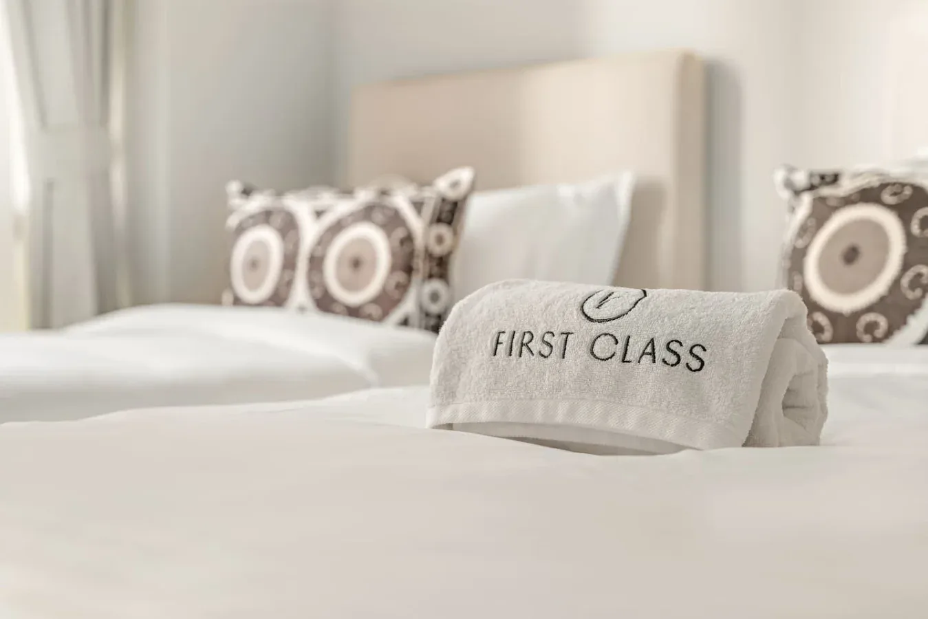 Un dormitorio con ropa de cama blanca y almohadas estampadas.