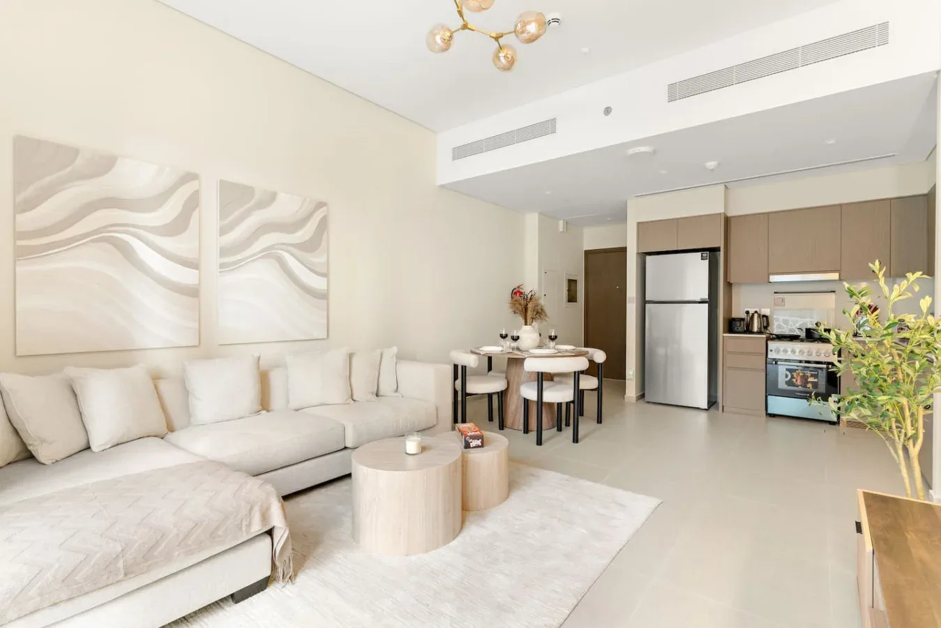 Una sala luminosa con zona de estar, mesa de comedor y cocina compacta.