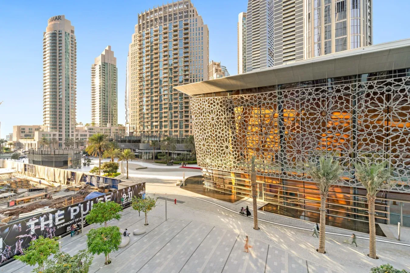 Una plaza urbana moderna está junto a una fachada estampada y altas torres.