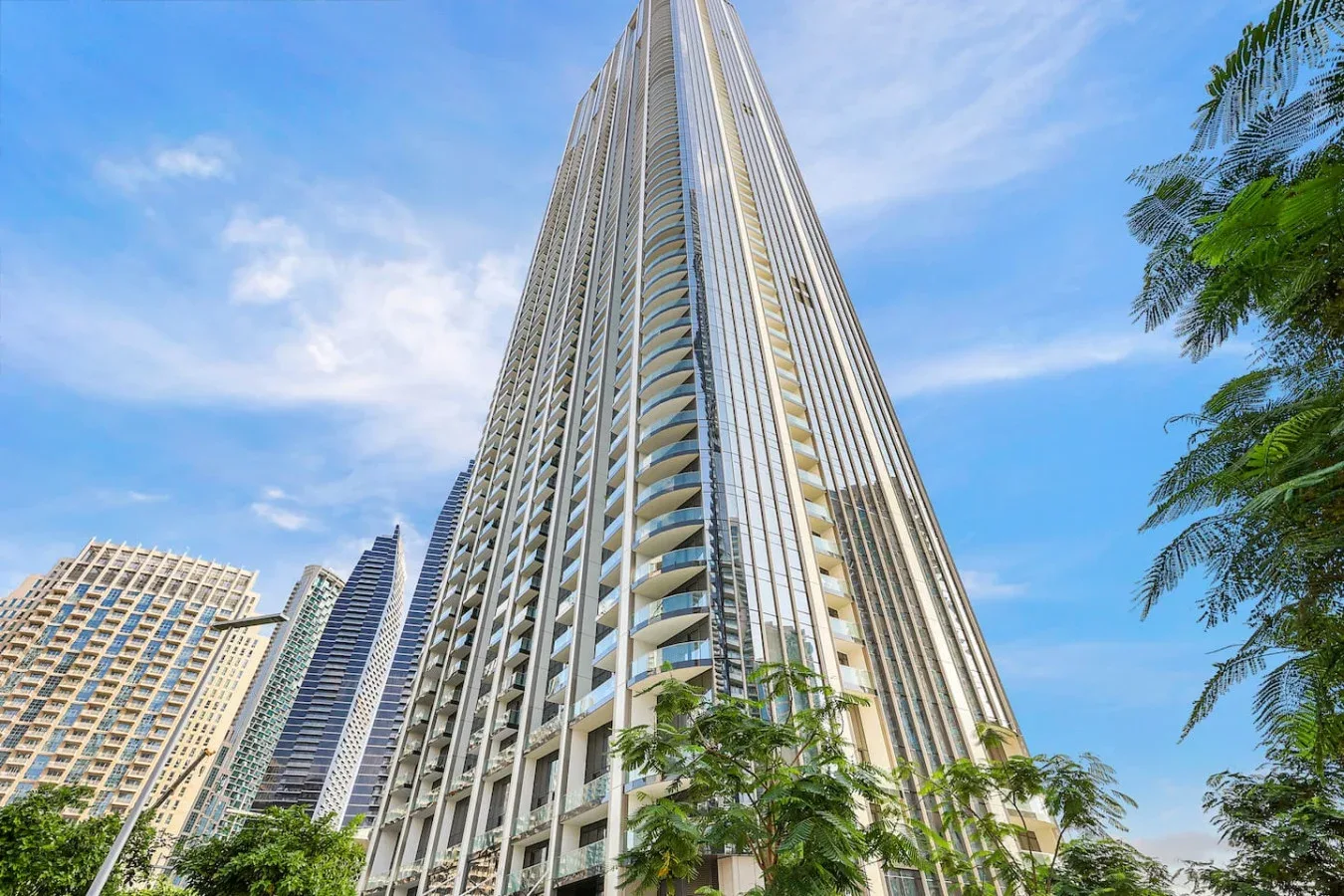 Un edificio alto se eleva sobre los árboles circundantes bajo un cielo azul.