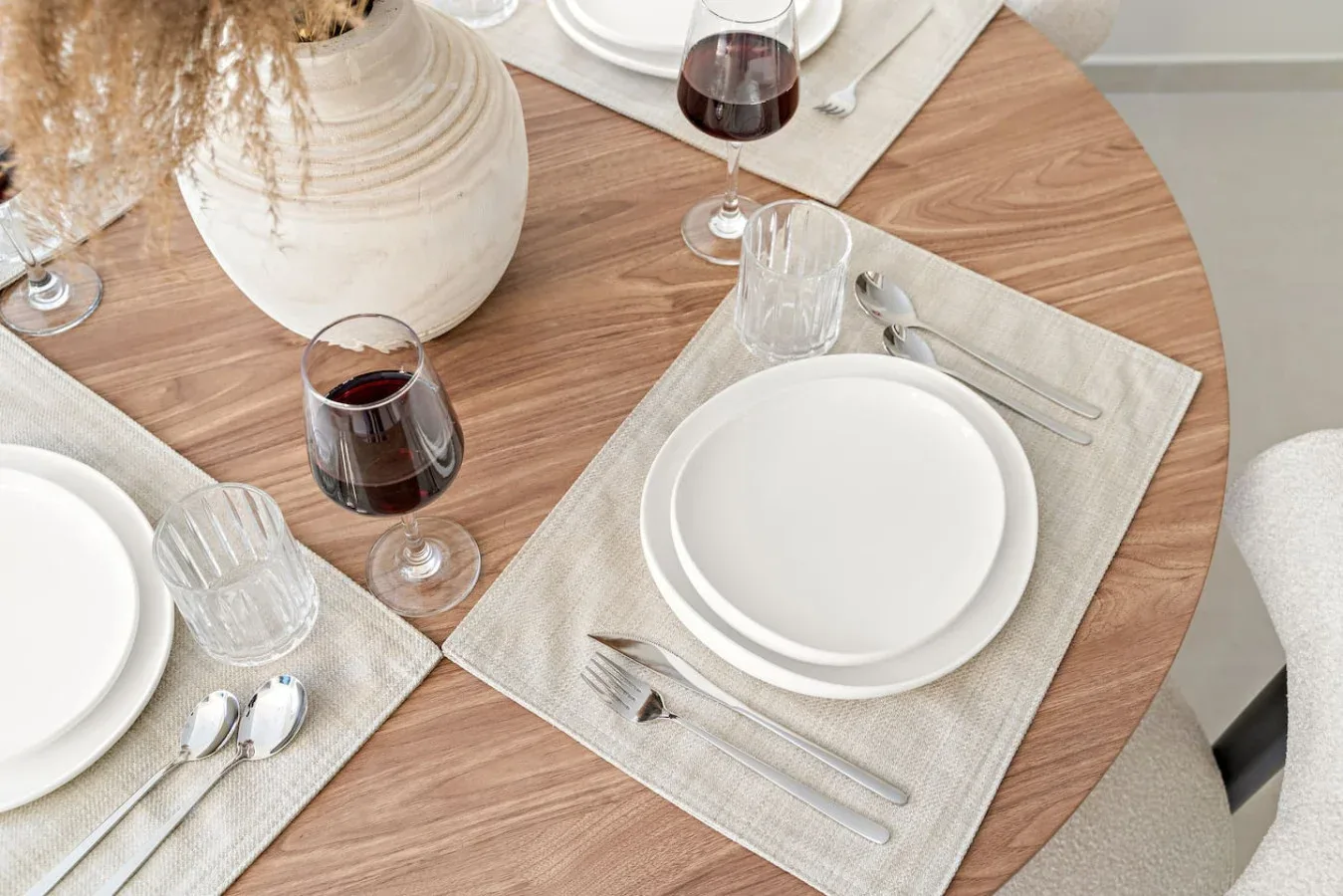 Una mesa de comedor está preparada con platos, vasos y cubiertos.