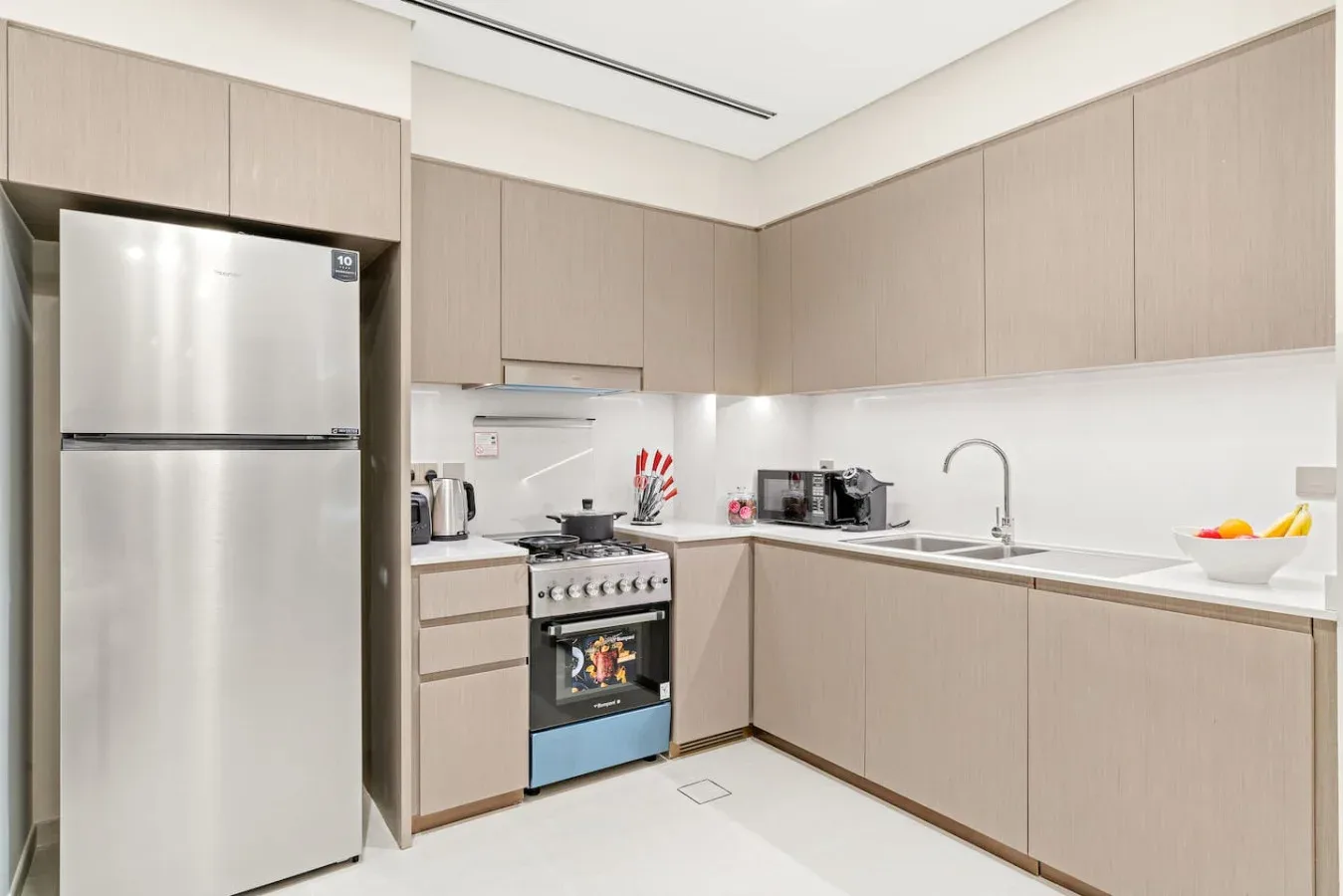 Una cocina moderna con gabinetes claros, refrigerador y estufa.