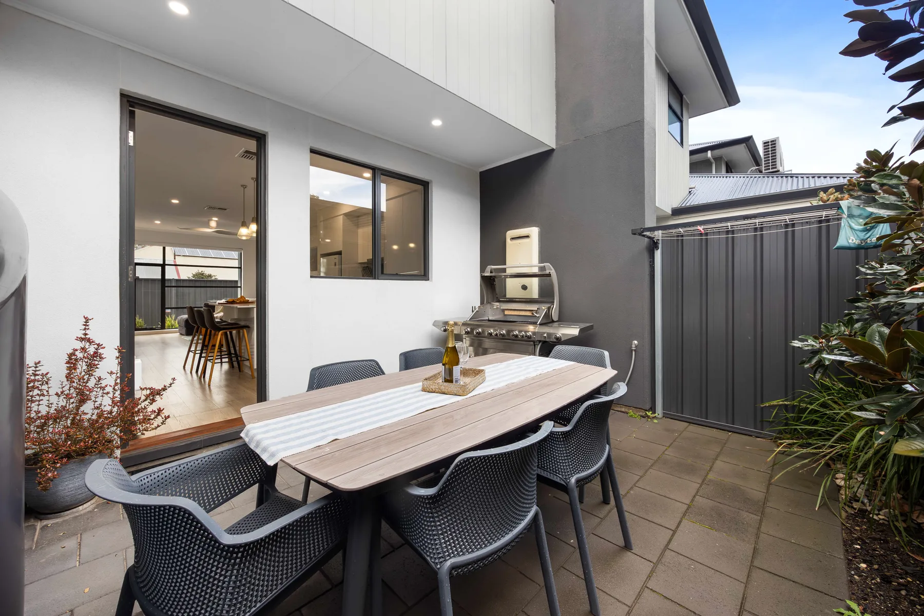 An outdoor dining area with a table and chairs beside a barbecue grill.