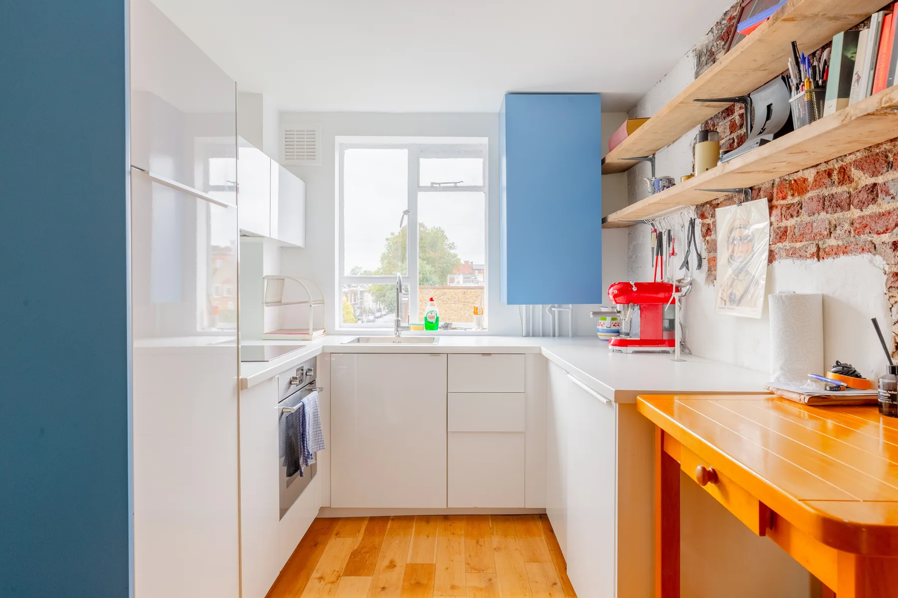 Una cocina luminosa con gabinetes blancos, una ventana y una mesa de trabajo de madera.