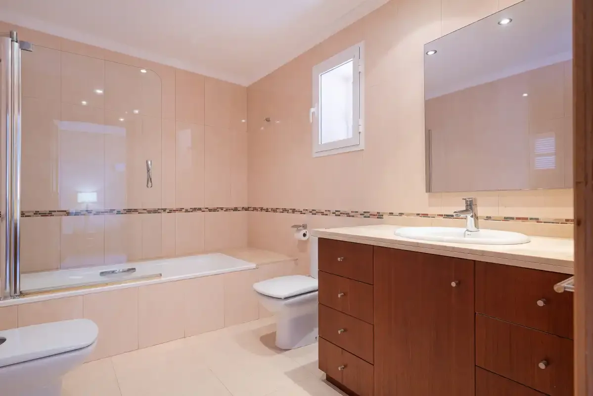 A bathroom with a bathtub, toilet, and sink vanity.