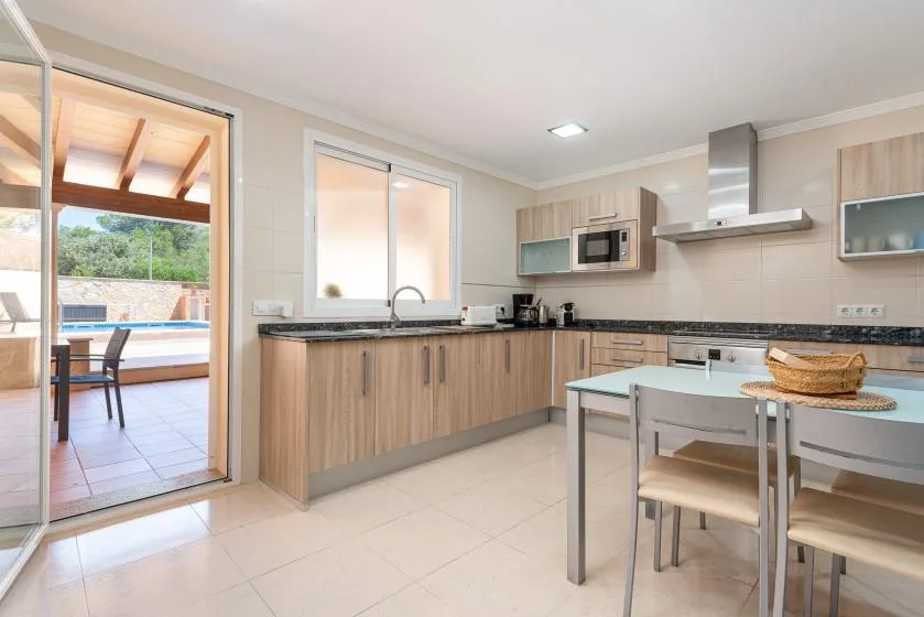 A bright kitchen with wood-toned cabinets, a dining table, and an open patio doorway.