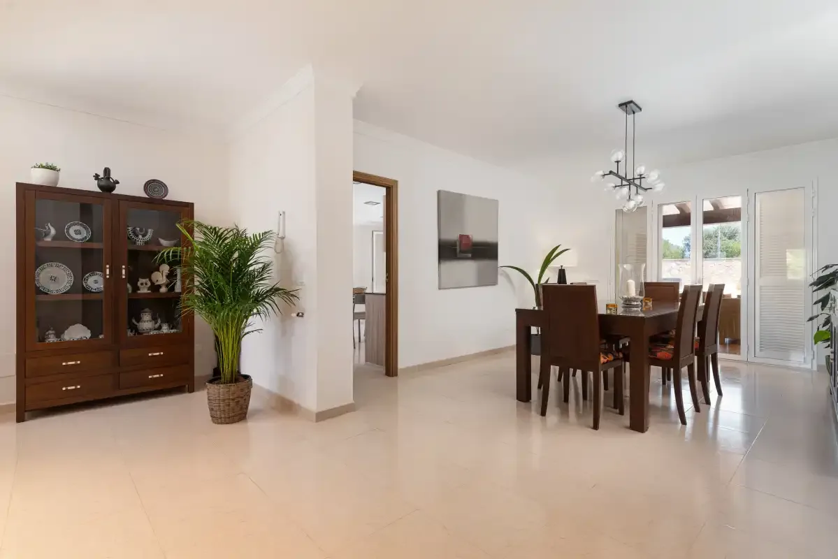 A bright dining area with a wooden table and chairs beside glass doors.