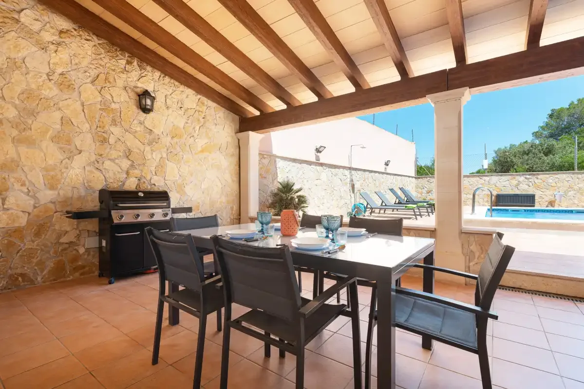 A covered patio dining area with outdoor seating and a barbecue.