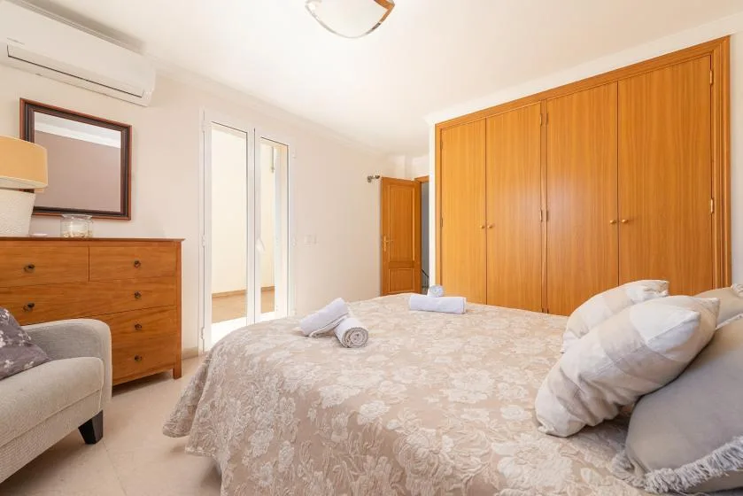 A bedroom with a large bed and a wall of wooden wardrobes.