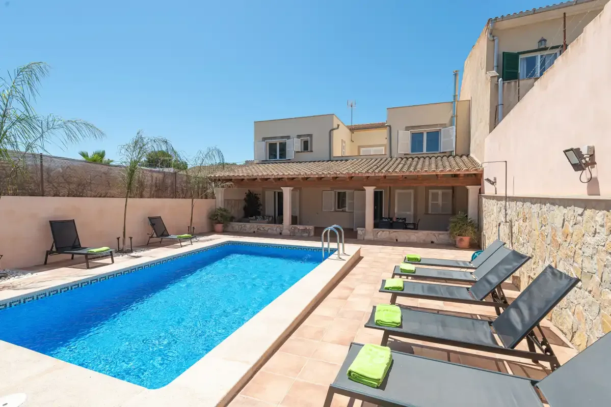 A sunny pool courtyard with lounge chairs arranged beside the water.