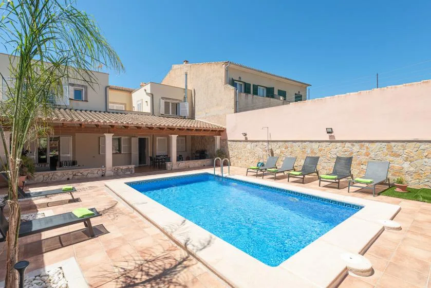 An outdoor swimming pool beside a shaded patio and surrounding buildings.