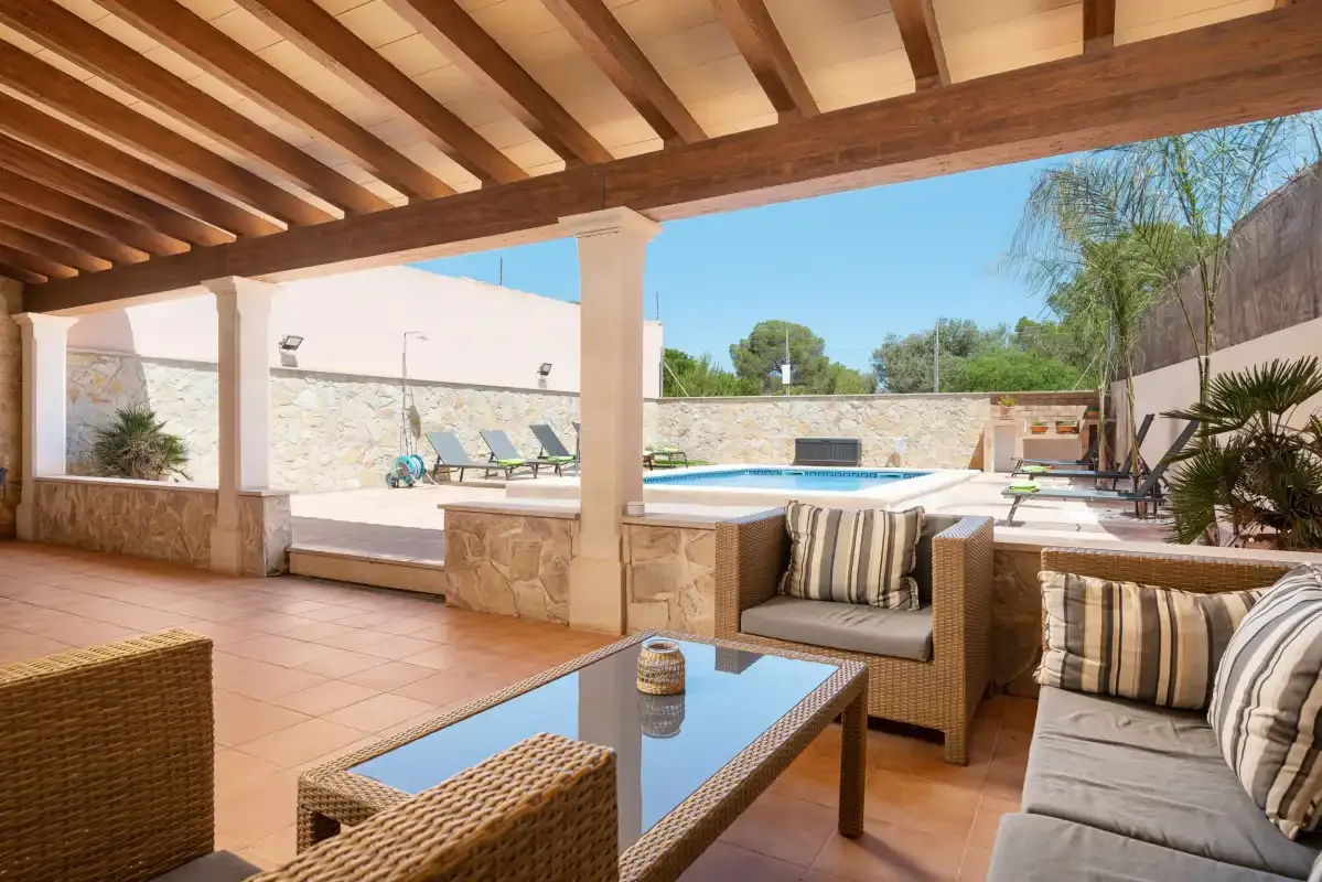 A covered patio seating area overlooks a swimming pool.