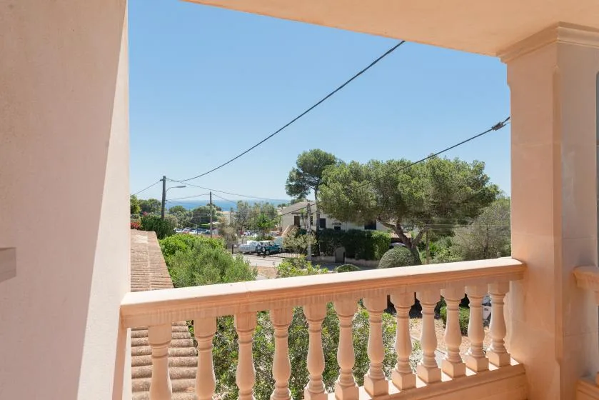 A balcony overlooks trees, rooftops, and a distant view beneath a clear sky.