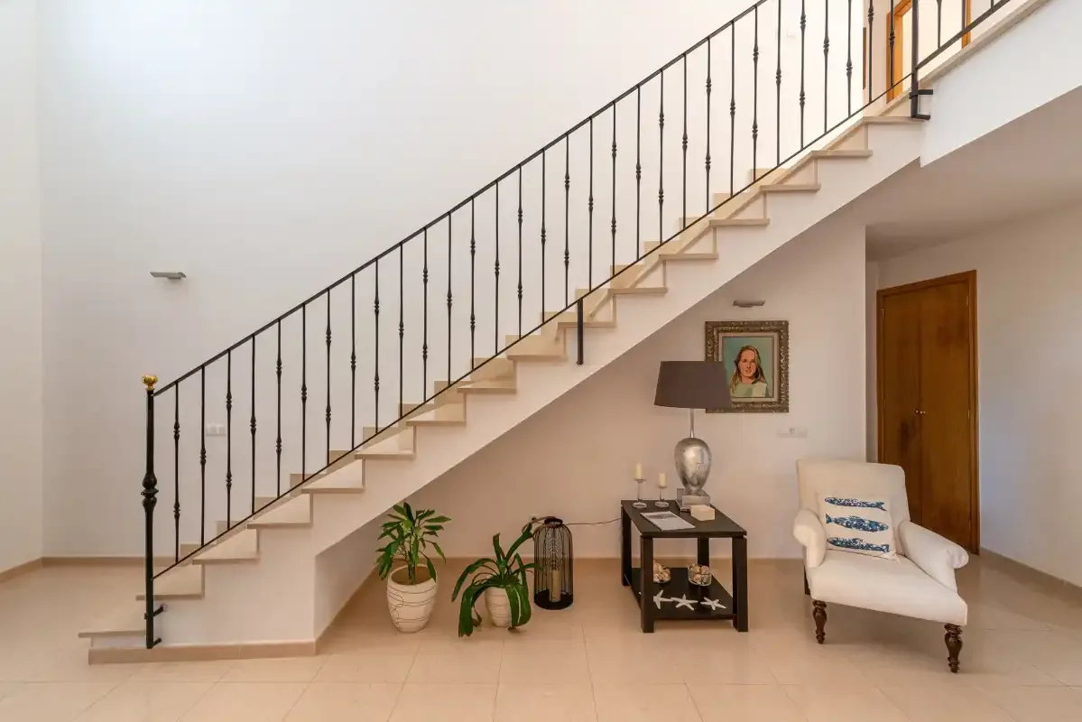 An interior stairway with a railing rises above a small seating area.