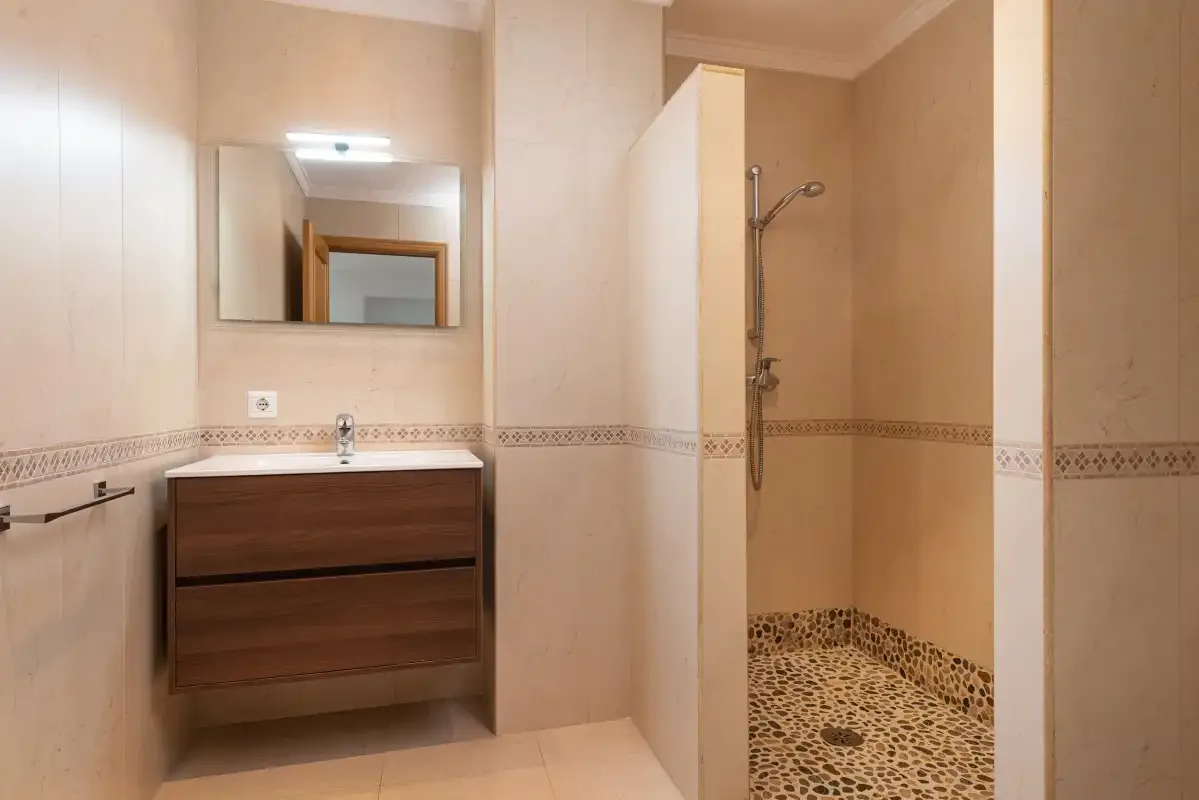 A bathroom with a floating vanity and an open shower area.