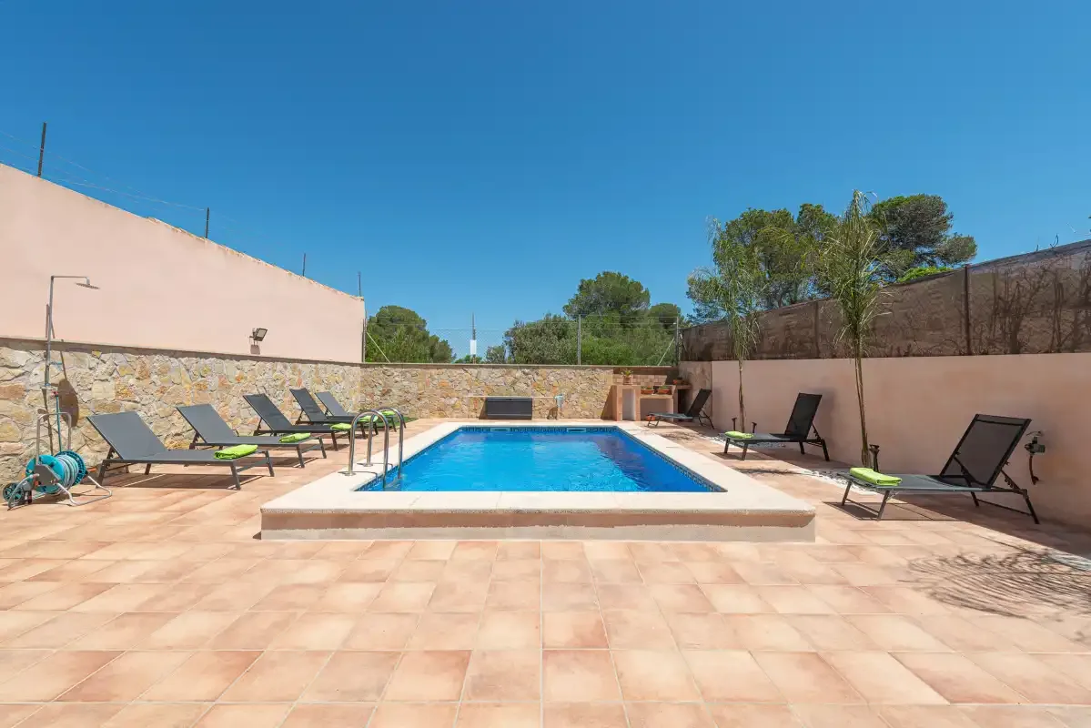 Outdoor pool area with a paved deck and lounge seating.