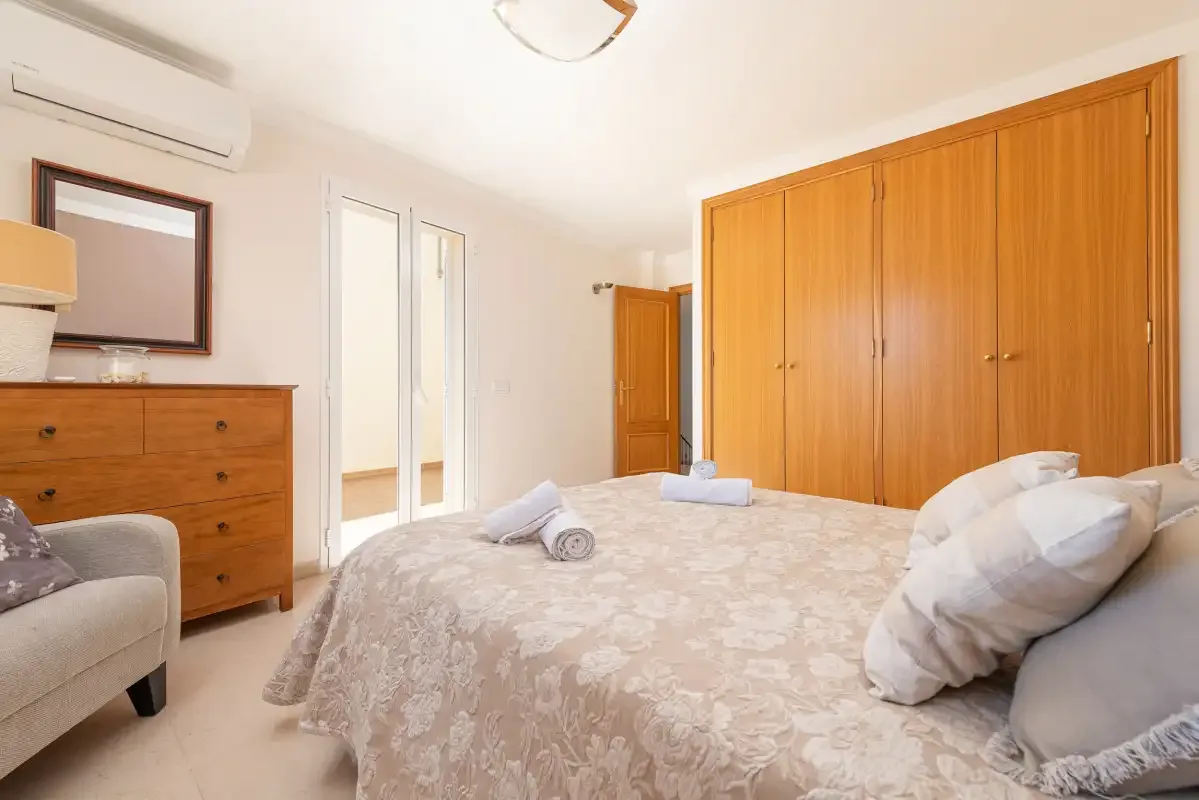 A bedroom with a large bed and wooden wardrobes.