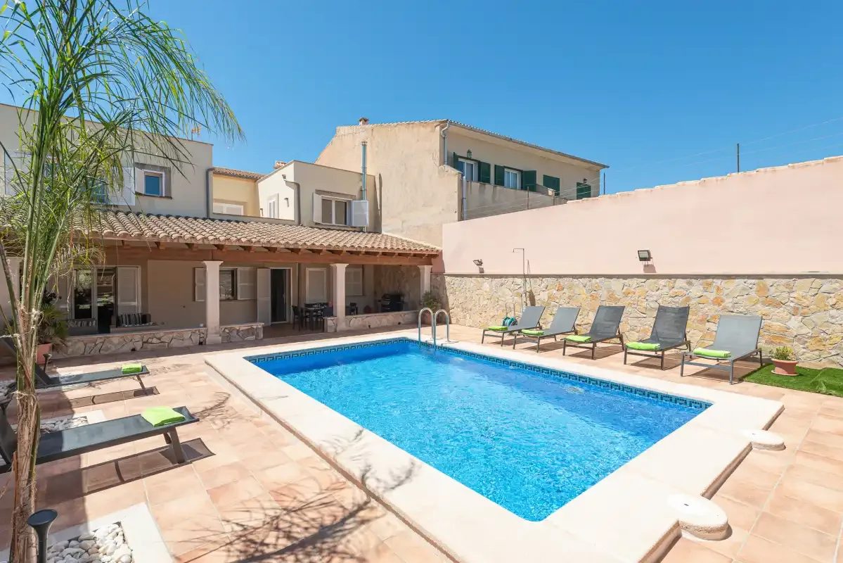 A sunny outdoor swimming pool beside a covered patio and seating.