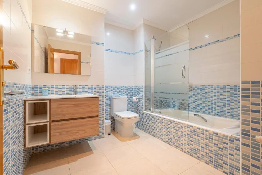 A tiled bathroom with a vanity, toilet, and glass shower area.