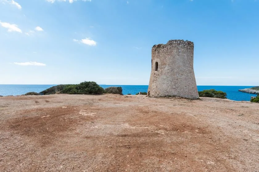 A stone tower stands on a rocky coastal plateau beside the sea.