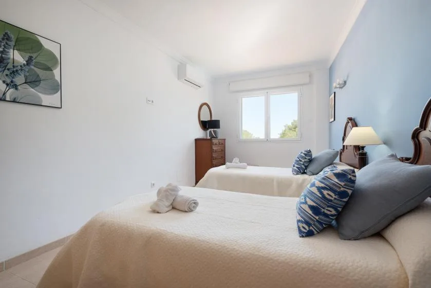 A bright bedroom with two beds and a window.