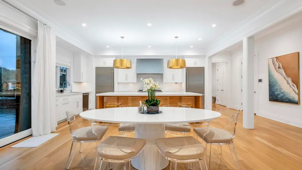 Una luminosa cocina abierta al comedor, con una gran isla y lámparas colgantes.