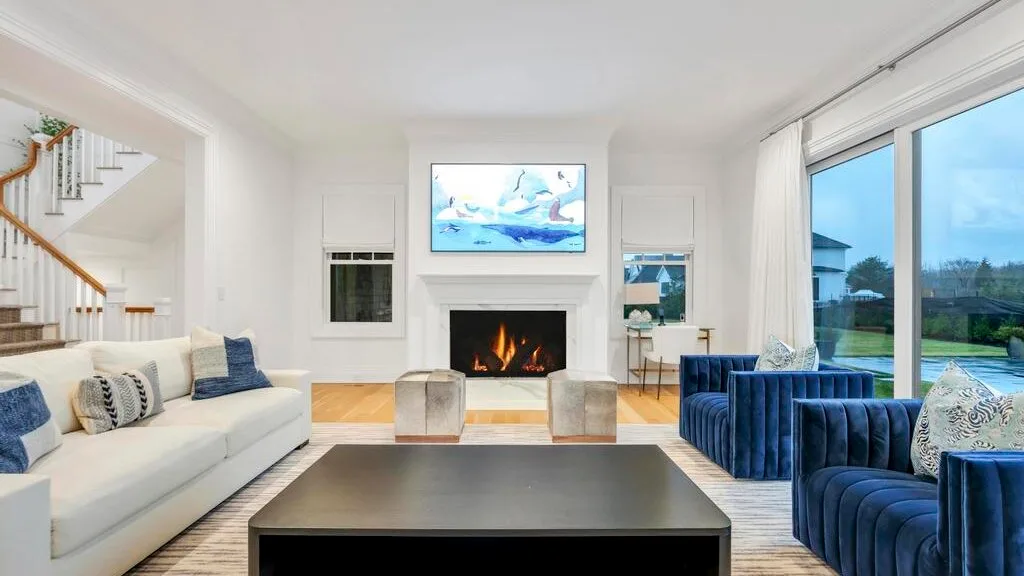 Una sala luminosa con asientos dispuestos alrededor de una chimenea y un televisor.