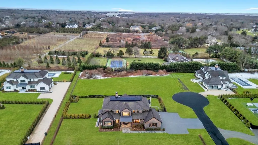 Vista aérea de una casa grande y jardines con un estanque.