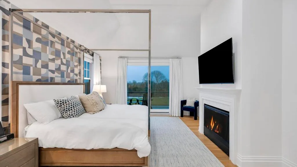 Un dormitorio con una cama grande, un televisor y una chimenea.