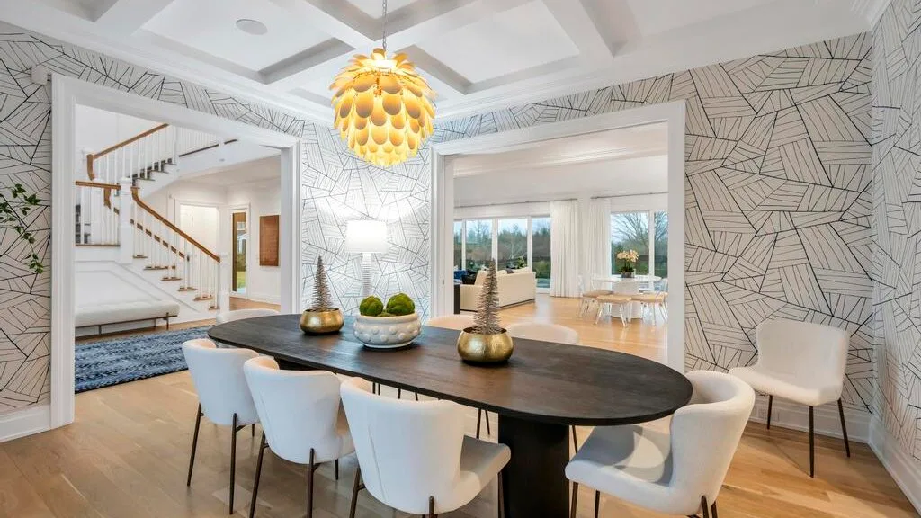 Un comedor con una mesa oscura y sillas está junto a una sala luminosa.