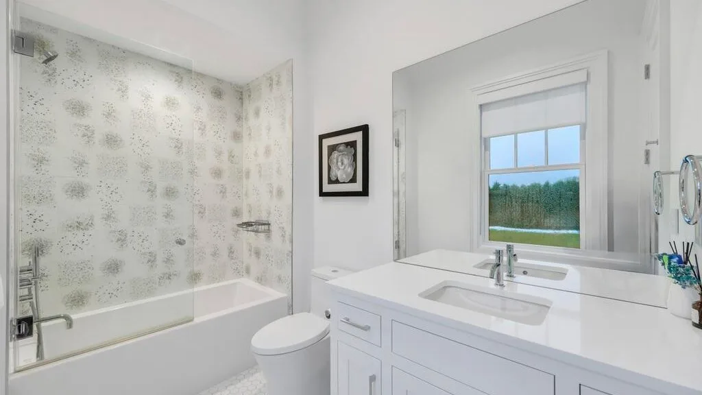 Un baño luminoso con bañera, inodoro y lavabo bajo una ventana.