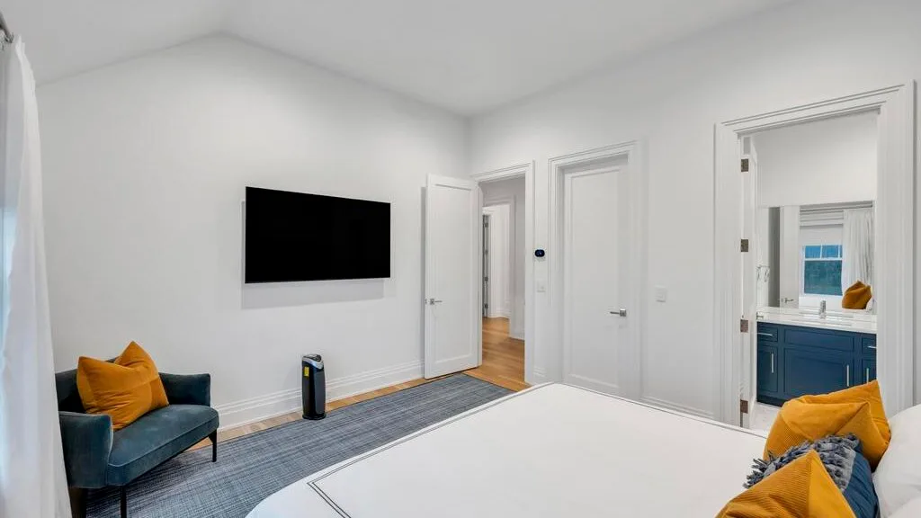 Una sala luminosa con asientos, un televisor en la pared y una alfombra grande.
