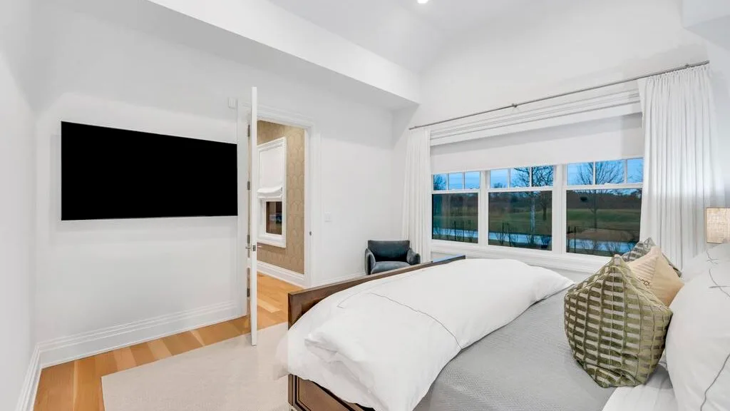 Un dormitorio luminoso con una cama grande junto a amplias ventanas.