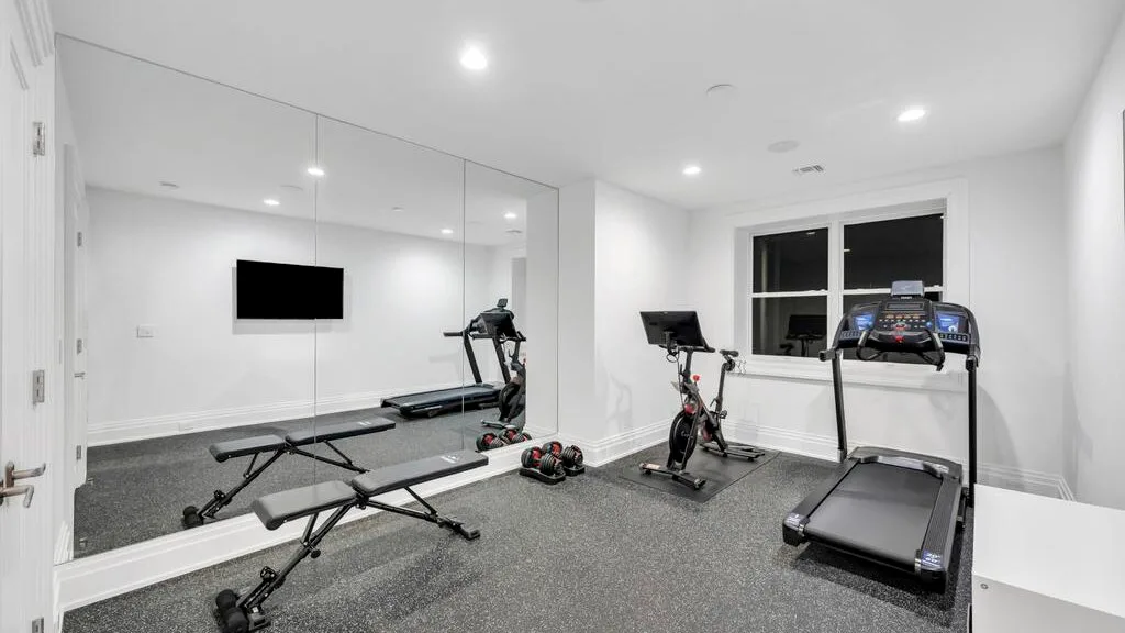 Un gimnasio en casa con máquinas de ejercicio y un espejo de pared.