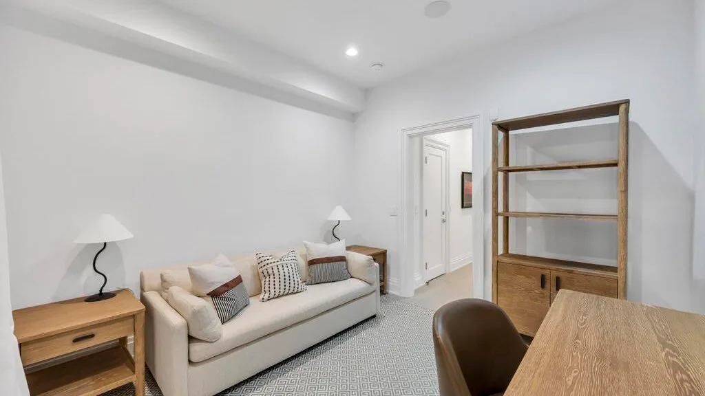 Una sala luminosa con un sofá, estanterías de madera y una mesa de comedor.