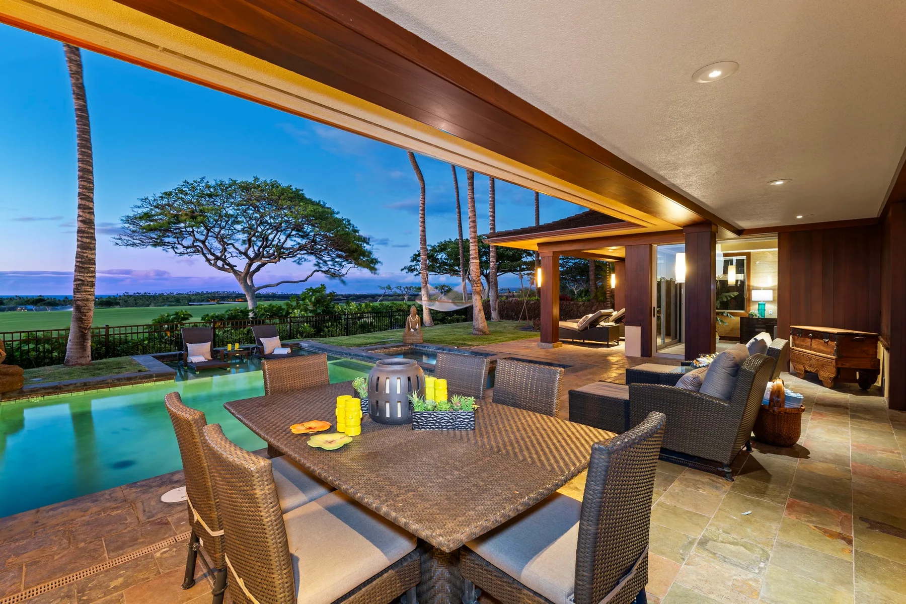 A covered outdoor dining area overlooks a swimming pool and landscaped grounds.