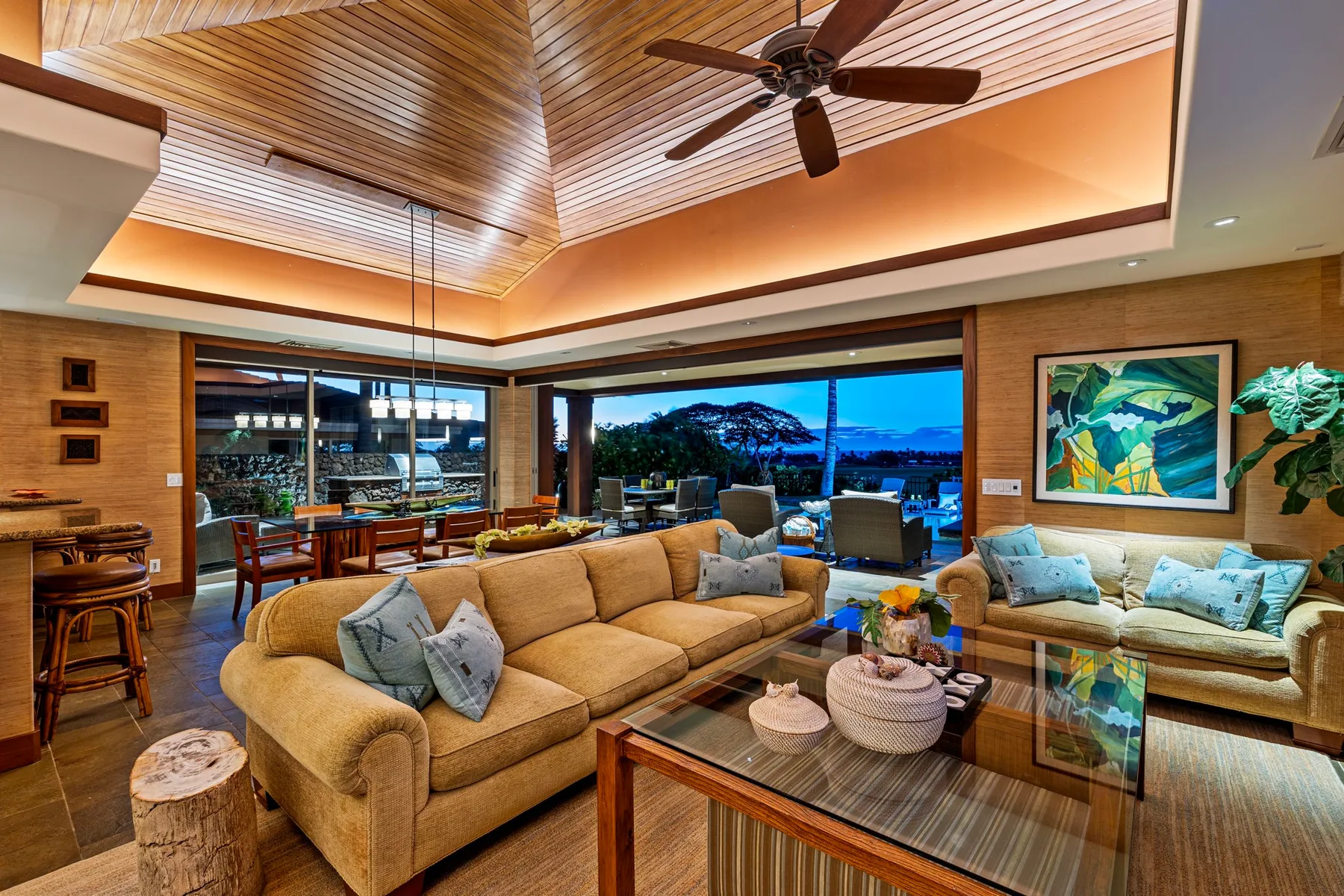 A spacious living room with seating, a glass coffee table, and large windows.