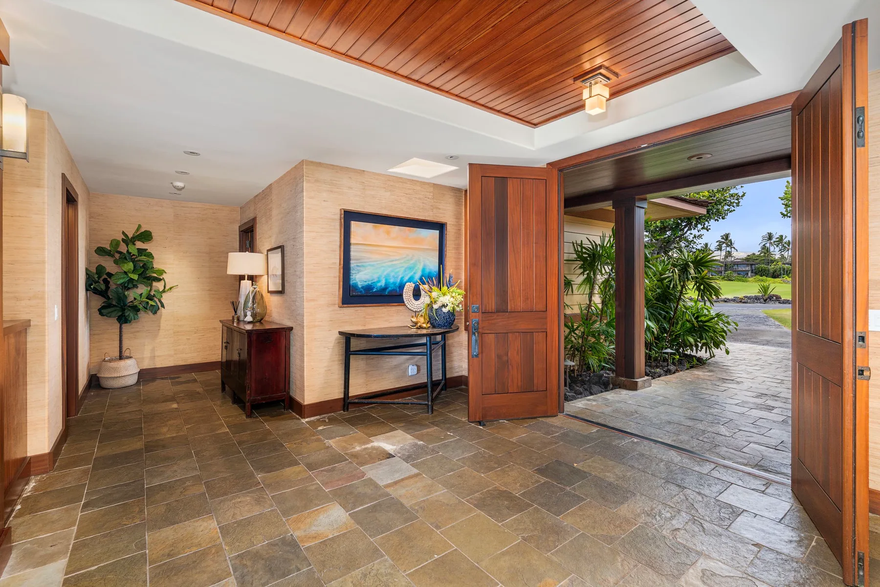 A tiled entry hall opens through wooden doors to a garden path.