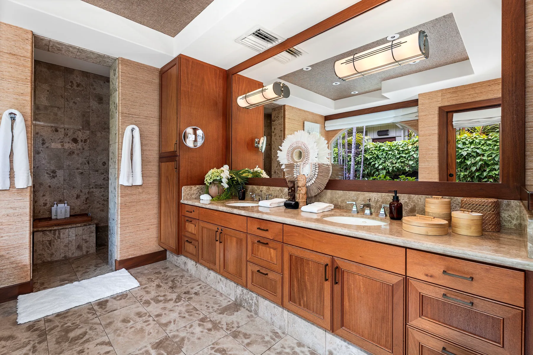 A spacious bathroom with a long wooden vanity, mirror, and open shower area.