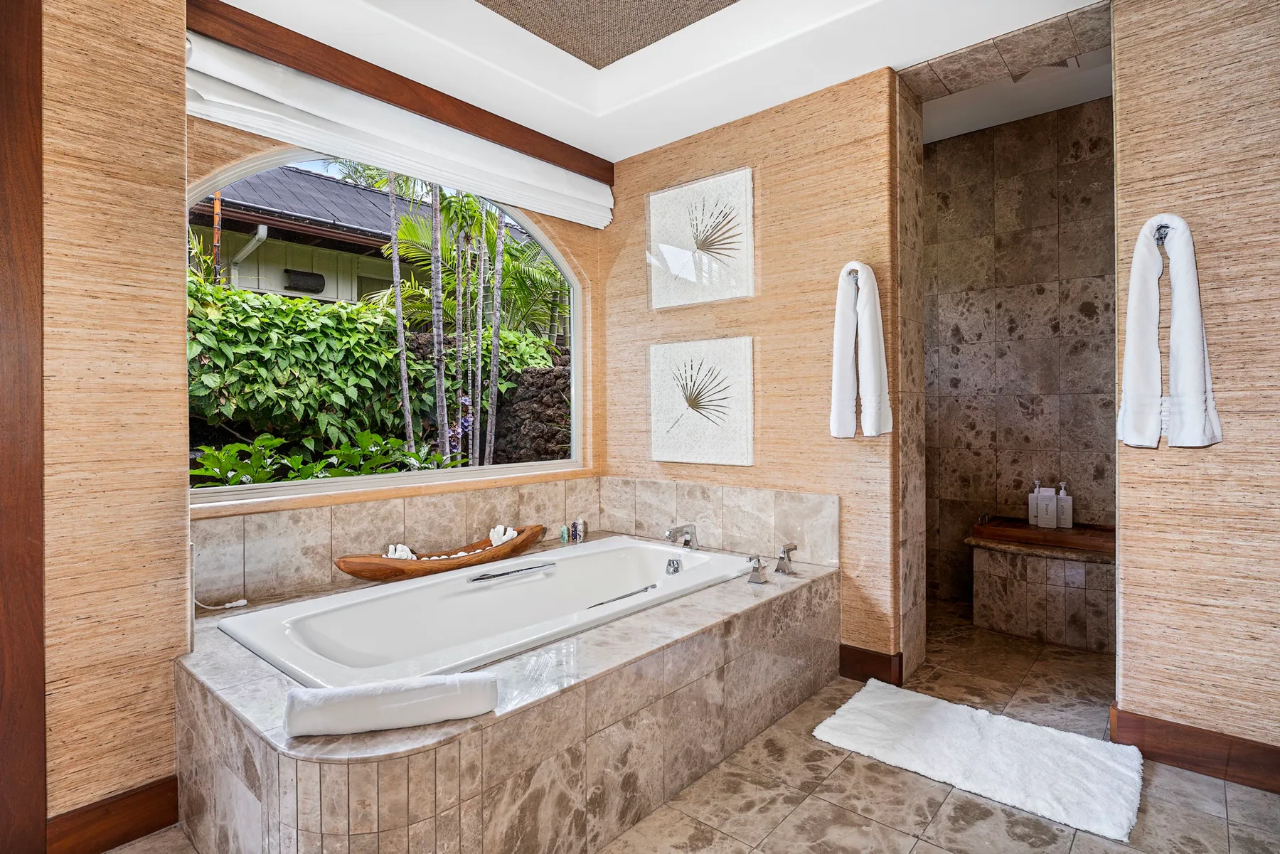 A bathroom with a built-in bathtub, a large window, and a tiled shower area.