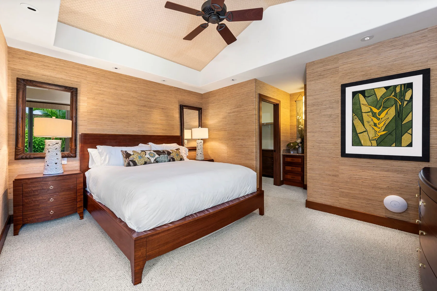A bedroom with a large bed, wooden furnishings, and framed artwork on the walls.