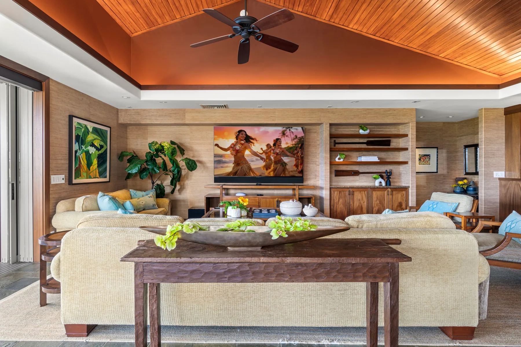 A living room with a large seating area, television, and wooden ceiling.
