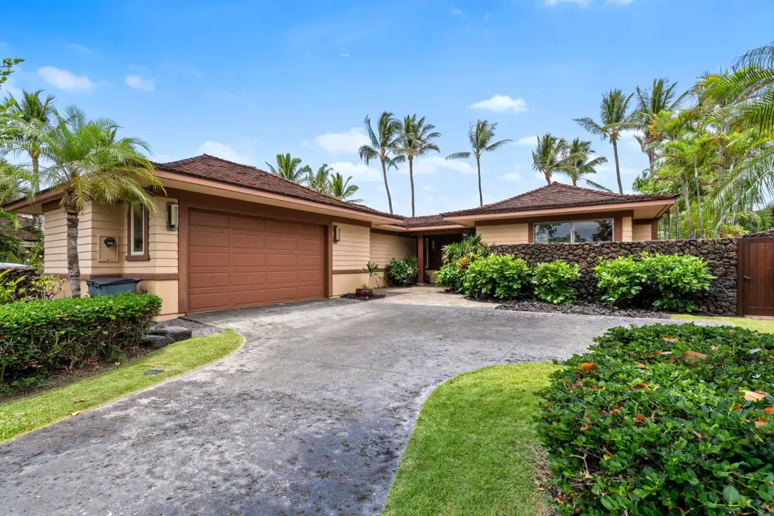 A single-story house with a brown garage door sits beside a curved driveway.