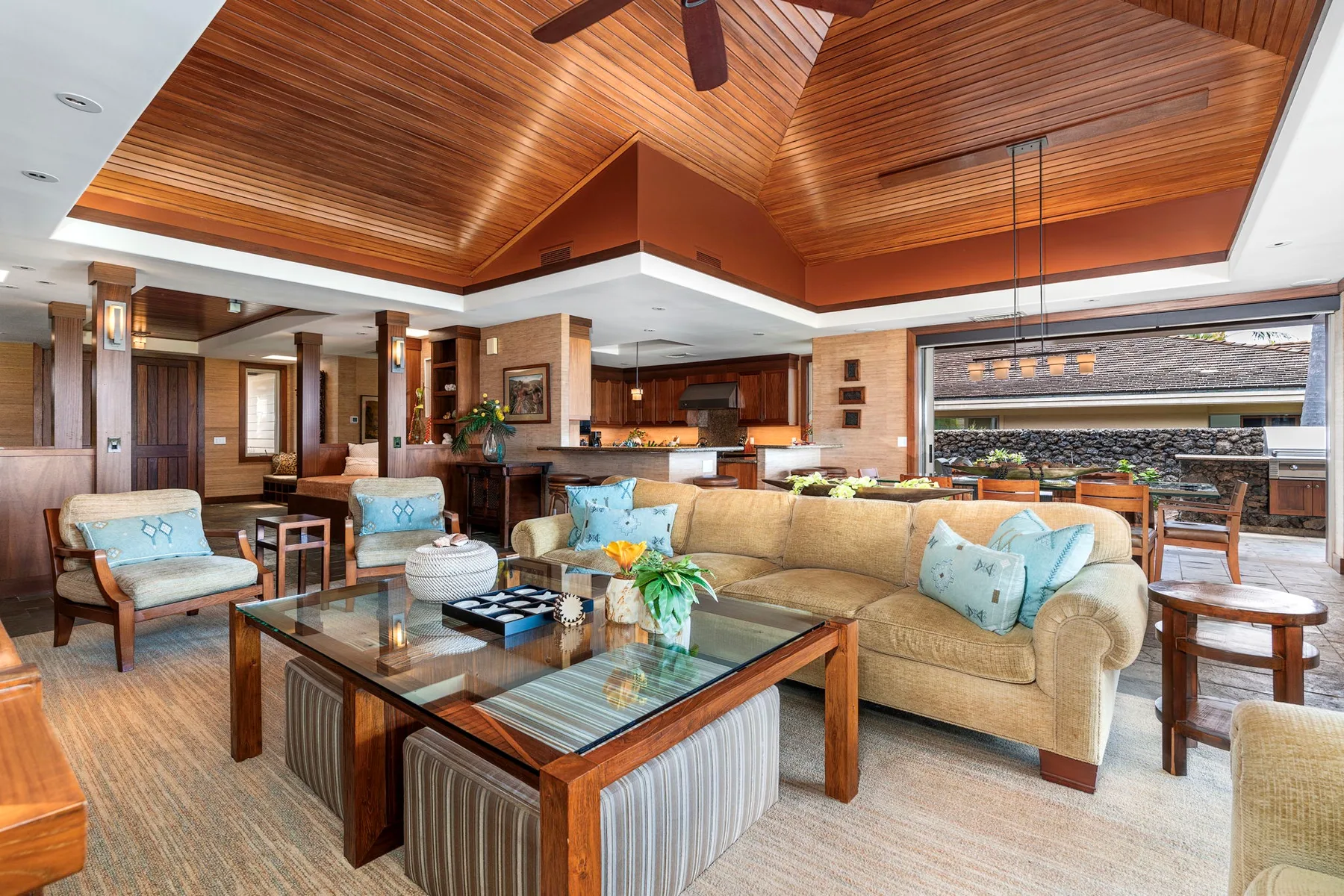 A spacious living room with cushioned seating and a large glass coffee table.